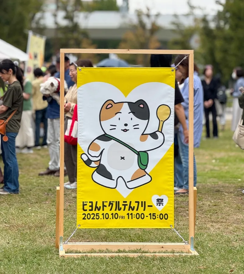第1回会場に立てられた猫のキャラクターのバナーと賑わう来場者